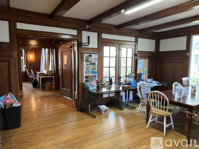 A room with wooden floors and furniture, including a desk and chairs.