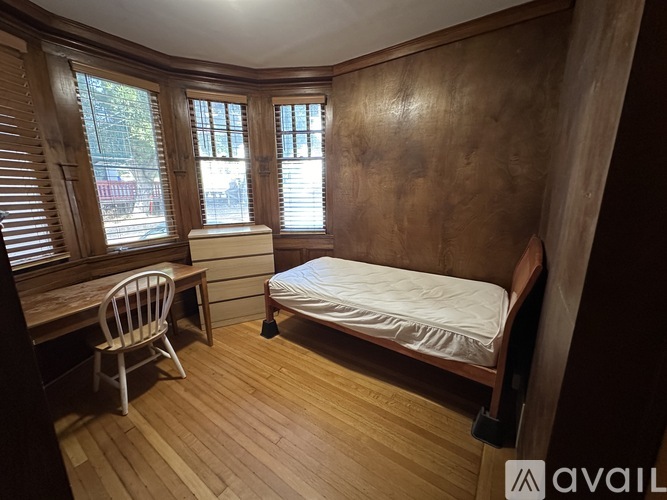 A bedroom with a bed, chair, and window.