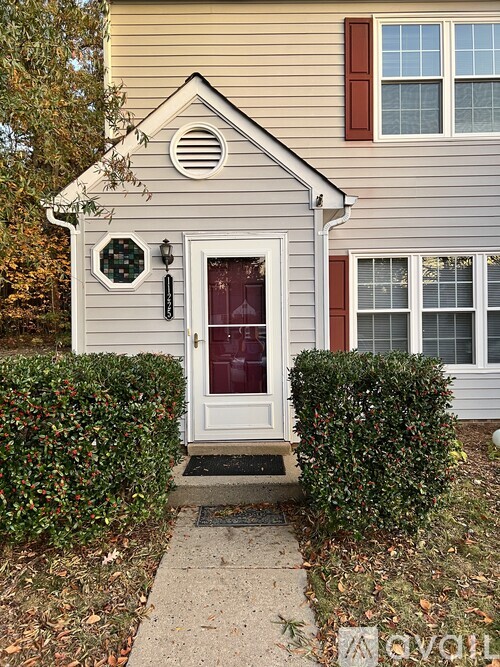 A small house with a white door and a window with red trim.