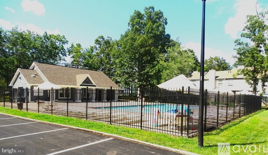 A black fence surrounds a pool area with a building in the background.