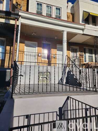 A balcony with a black railing and a white wall.