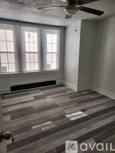 A room with a ceiling fan and a window with blinds.