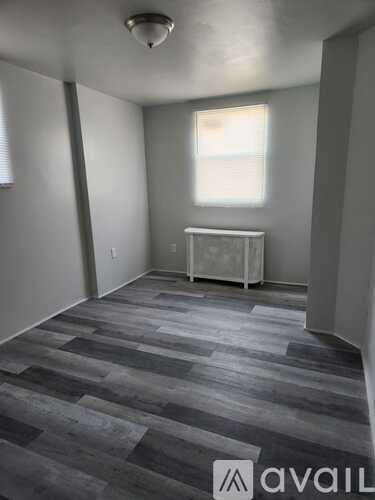 A room with grey flooring and a white cabinet under a window.
