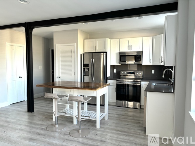 A modern kitchen with a wooden table and stainless steel appliances.