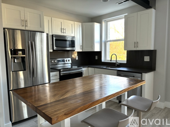 A kitchen with a wooden table and stainless steel appliances.