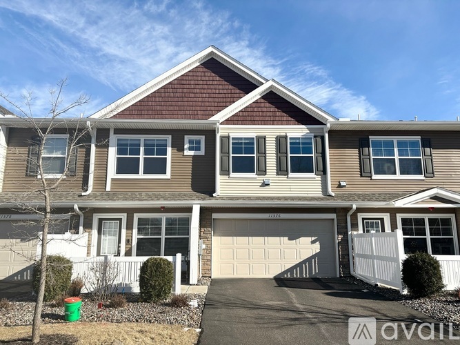 A house with a brown roof and a white fence is for sale.