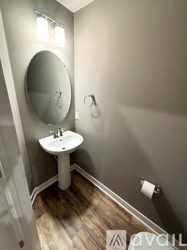 A bathroom with a sink, mirror, and toilet paper holder.