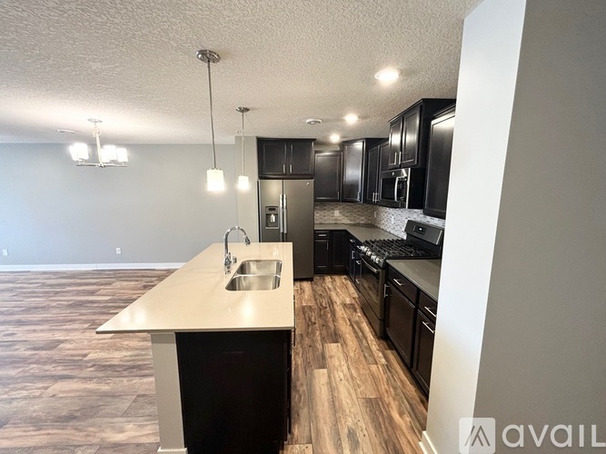 A kitchen with black cabinets and a wooden floor.