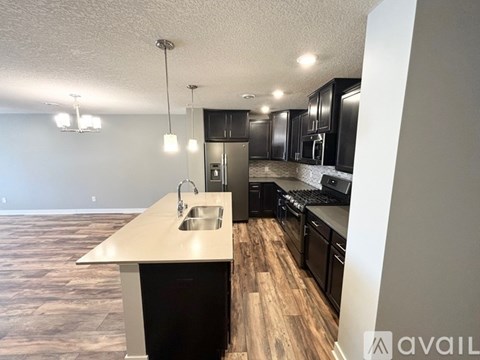 A kitchen with black cabinets and a wooden floor.