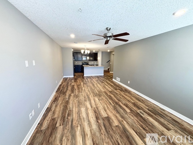 A spacious room with wooden flooring and a ceiling fan.