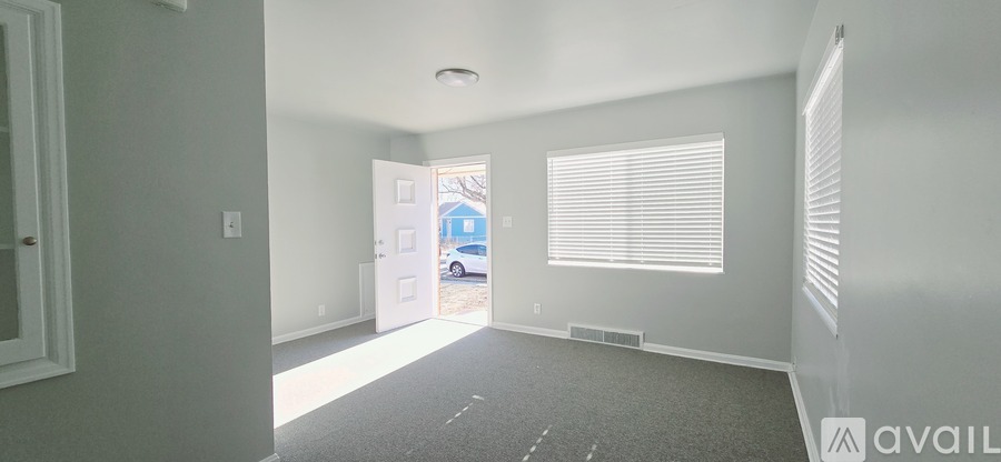 A room with a carpeted floor and a window with blinds.