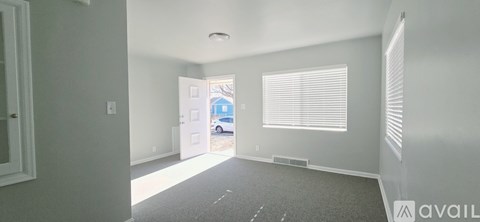A room with a carpeted floor and a window with blinds.