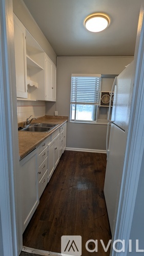 A kitchen with white cabinets and a wooden floor.