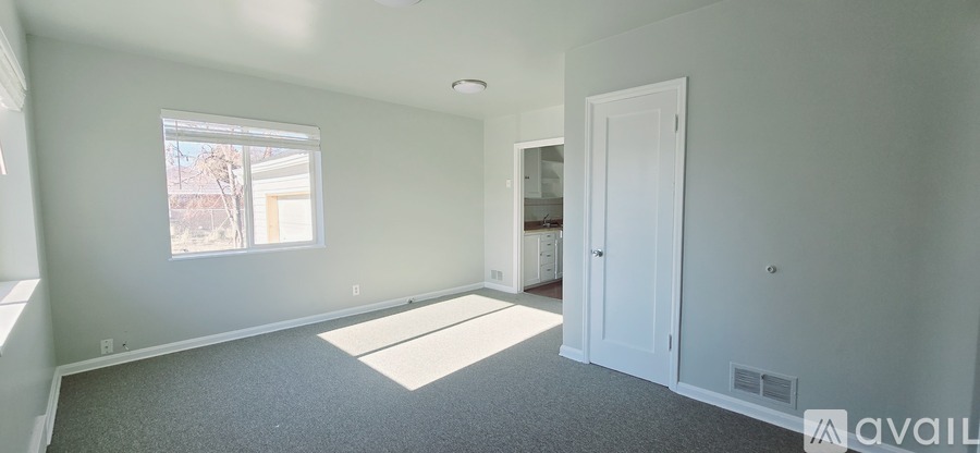 A room with a carpeted floor and a window letting in sunlight.
