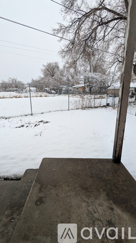 A snowy landscape with a fence and trees in the distance.