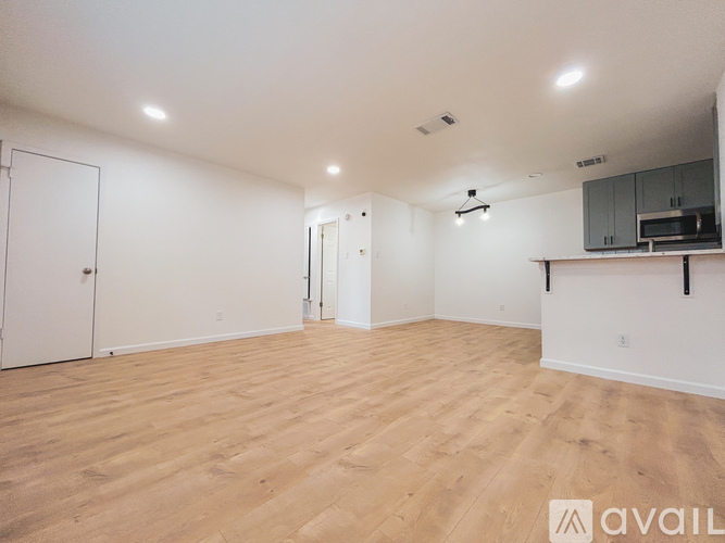 A spacious room with wooden flooring and white walls.