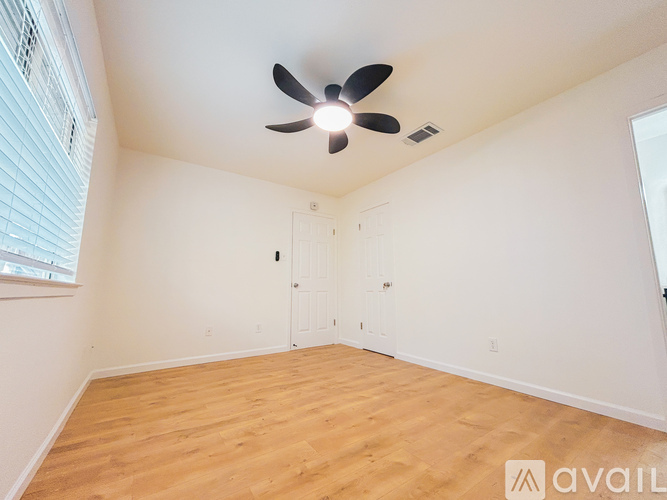 A room with a ceiling fan and wooden flooring.