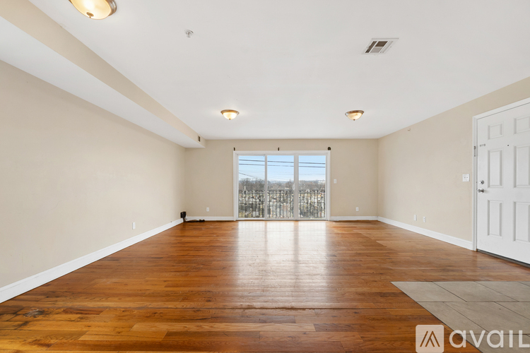 A spacious room with wooden flooring and a sliding glass door.