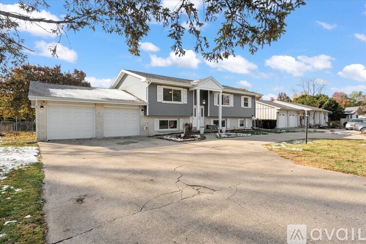 A house with a grey roof and white garage doors is available for sale.
