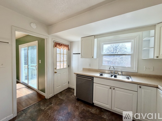 A kitchen with white cabinets and a window with a view of trees outside.