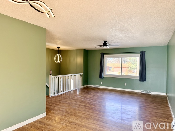 A room with a ceiling fan and a window with black curtains.