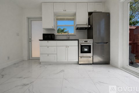 A kitchen with white cabinets and marble flooring.