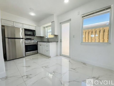 A kitchen with white cabinets and a marble floor.