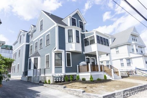 A large house with a grey and white exterior and a balcony.