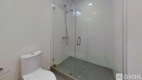 A white toilet sits next to a glass shower stall.