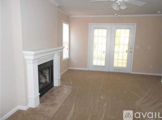 A living room with a fireplace and a fan on the ceiling.