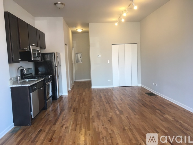A kitchen with black cabinets and a wooden floor.