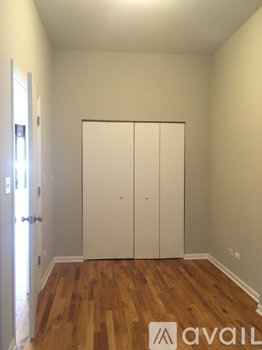 A room with a white door and a wooden floor.