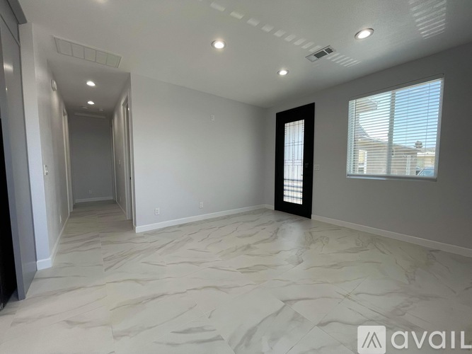 A spacious room with a marble floor and a window with blinds.