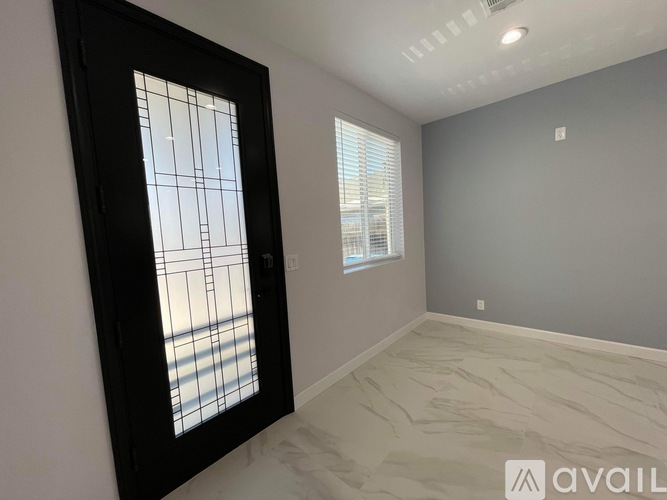 A room with a black door and a window with a grid pattern.