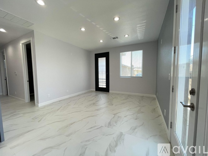 A spacious room with marble flooring and a door leading to a balcony.