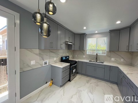A kitchen with grey cabinets and a marble countertop.