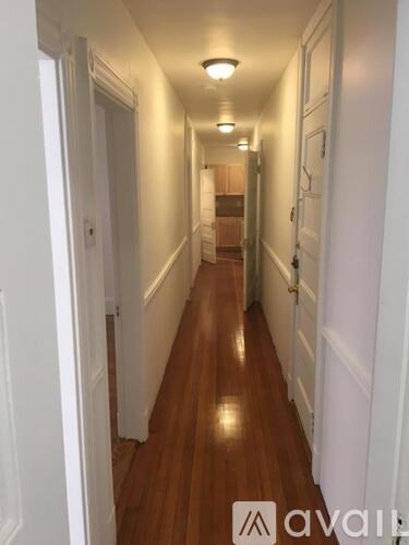 A long hallway with wood floors and white walls.