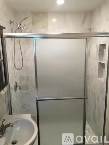 A bathroom with a glass shower door and a white sink.