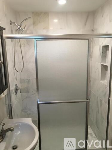 A bathroom with a glass shower door and a white sink.