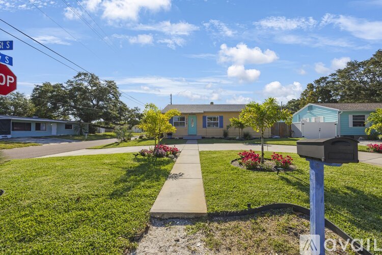 A blue mailbox sits on a sidewalk in front of a house.