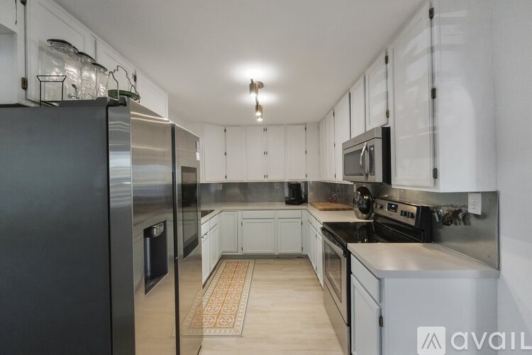 A kitchen with a black refrigerator and stainless steel appliances.