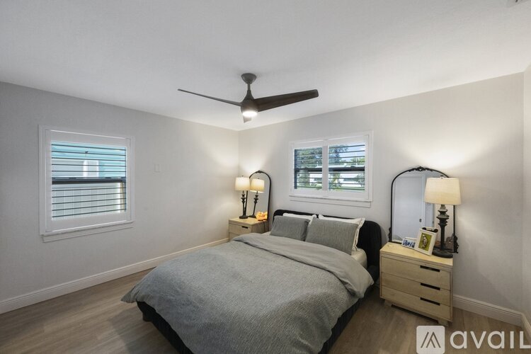 A bedroom with a bed, two nightstands with lamps, and a ceiling fan.