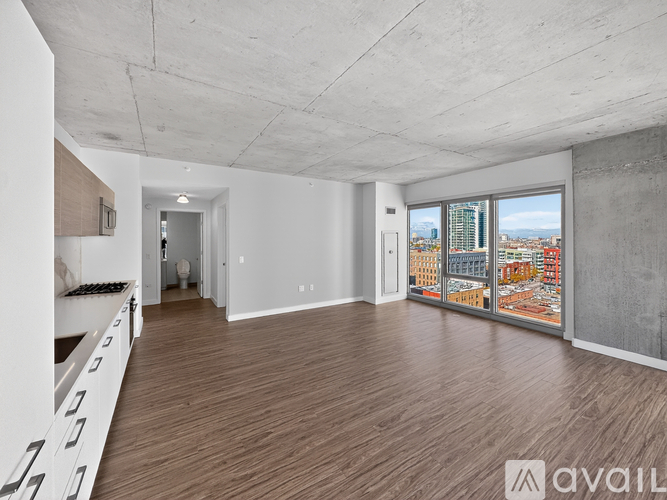 A spacious room with wooden flooring and a large window overlooking a cityscape.