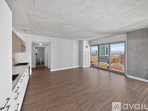 A spacious room with wooden flooring and a large window overlooking a cityscape.