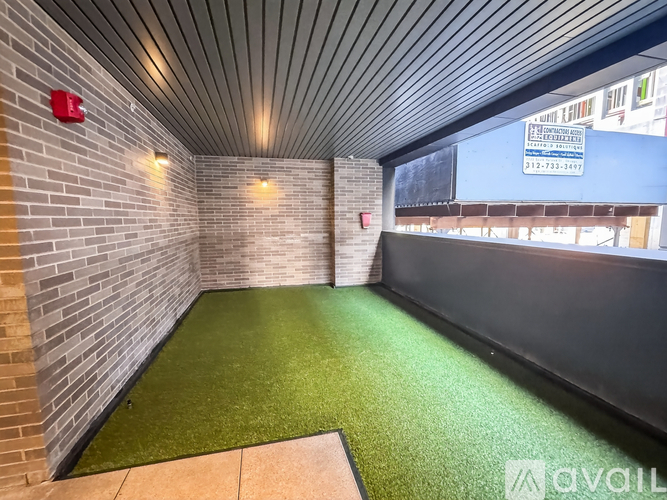 A small room with artificial grass and a brick wall.
