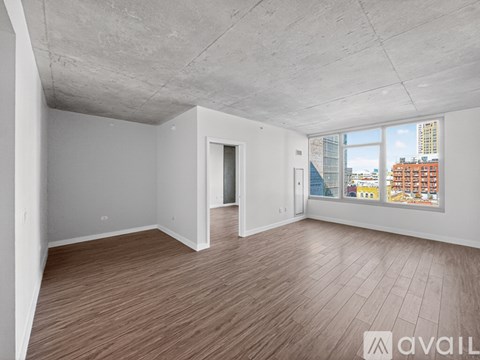 A spacious room with wooden flooring and a view of the city through the window.