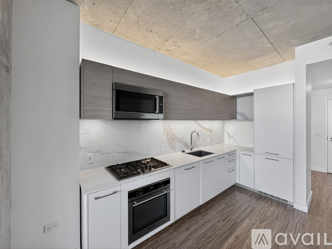 A modern kitchen with white cabinets and a wooden floor.