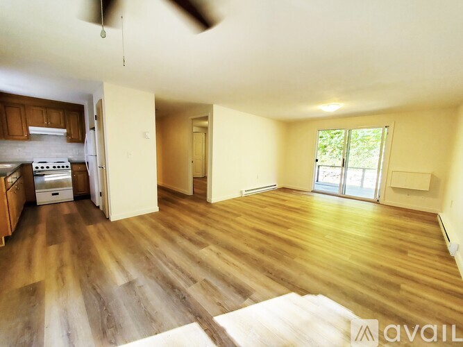 A room with wooden floors and a window with a view of trees.