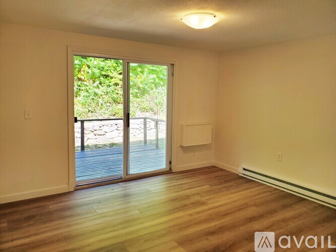 A room with wooden floors and a sliding glass door leading outside.