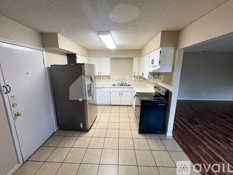 A kitchen with a black fridge, white cabinets, and a white door.